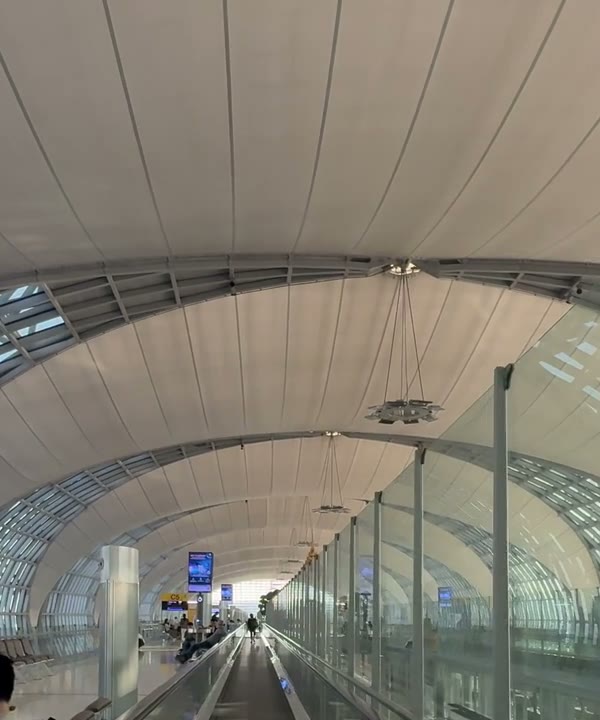 A bright airport walkway under a glass roof